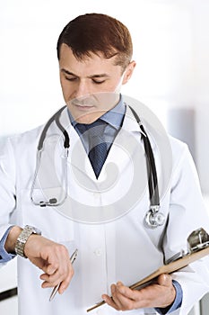 Doctor man using clipboard for filling up medication history records. Perfect medical service in clinic. Physician at