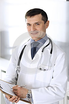 Doctor man using clipboard for filling up medication history records. Perfect medical service in clinic. Physician at