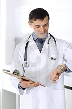 Doctor man using clipboard for filling up medication history records. Perfect medical service in clinic. Physician at