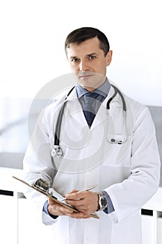 Doctor man using clipboard for filling up medication history records. Perfect medical service in clinic. Physician at