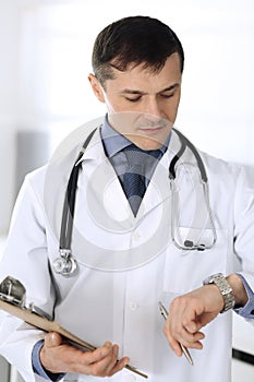 Doctor man using clipboard for filling up medication history records. Perfect medical service in clinic. Physician at