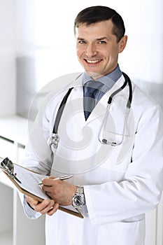 Doctor man using clipboard for filling up medication history records. Perfect medical service in clinic. Physician at