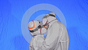 Doctor man and woman in protective costume suit, gas protect medical spray paint mask. Love couple kiss and hug, health