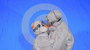 Doctor man and woman in protective costume suit, gas protect medical spray paint mask. Love couple kiss and hug, health