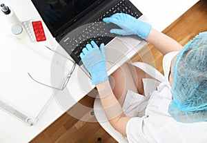 A doctor in a mask and gloves works on a computer in a polyclinic, a hospital in an emergency room.Doctor woman at work. reception