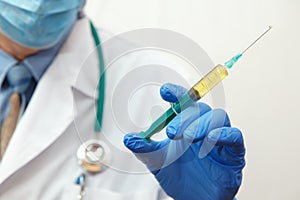 Doctor in mask holding a medical injection syringe