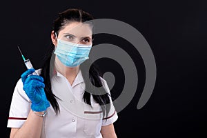 Doctor in mask holding a syringe, closeup, vaccination and immunization concept, isolated on dark