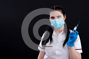 Doctor in mask holding a syringe, closeup, vaccination and immunization concept, isolated on dark