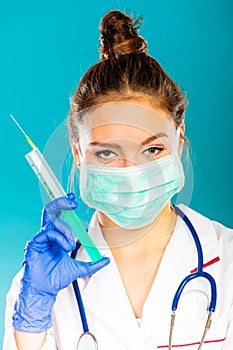 Doctor in mask holding syringe with injection