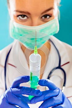 Doctor in mask holding syringe with injection