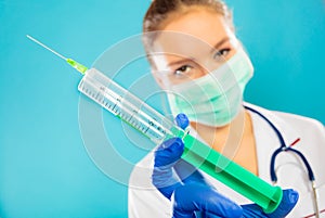 Doctor in mask holding syringe with injection