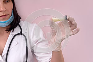 Doctor in mask looking at ampoule with medicament