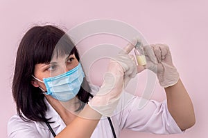 Doctor in mask looking at ampoule with medicament