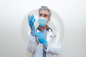 Doctor with mask in uniform putting on gloves with a white background