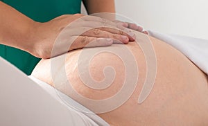 Doctor masseur chiropractor makes a light massage to a pregnant girl for skin tone and removal of stretch marks on the