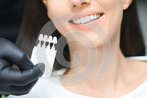 Doctor matching patient's teeth color with palette, closeup. Cosmetic dentistry