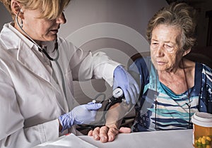Doctor measures the arterial tension to oldster at home