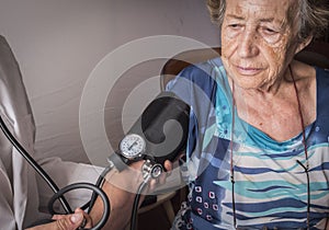 Doctor measures the arterial tension to oldster at home