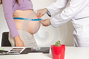 The doctor measures the belly of a pregnant woman with a measuring tape. The concept of the development of pregnancy