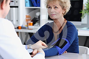 Doctor measures blood pressure of an elderly woman in medical office