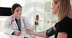 Doctor measures blood pressure of female patient with device