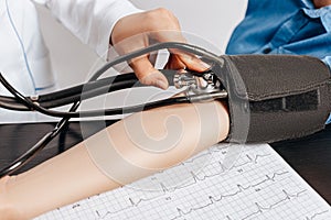 Doctor measures blood pressure with a tonometer to a woman patient at a medical appointment in a clinic