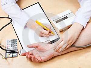 Doctor measures blood pulse of patient