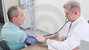 The doctor measures the patient's blood pressure in the hospital during the appointment.