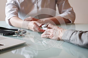 Doctor measures patient`s oxygen saturation and pulse using pulse oximeter in a clinic