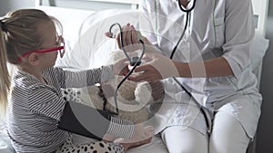 The doctor measures the pressure of the little girl in the hospital