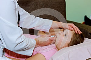 Doctor measures temperature of sick little girl on bed. Doctor checking thermometer