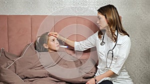 Doctor measures temperature of teen girl in bedroom at home