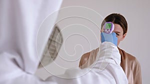 Doctor measures the temperature of woman with an infrared thermometer in clinic