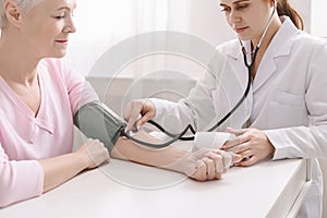 Doctor measuring arterial blood pressure for senior patient