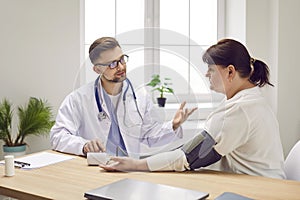 Doctor measuring blood pressure of fat overweight young woman in medical clinic.