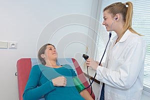 Doctor measuring blood pressure pregnant woman in clinic photo
