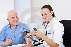 Doctor measuring blood pressure of senior man