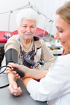 Doctor measuring blood pressure of senior patient