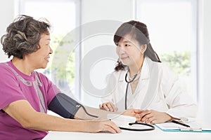 Doctor measuring blood pressure of senior woman
