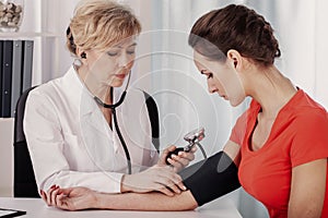 Doctor measuring blood pressure of young female patient in medical clinic