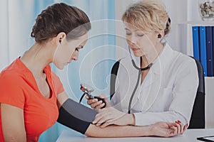 Doctor measuring blood pressure of young female patient in medical clinic