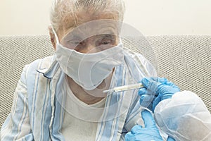 Doctor measuring body temperature at elderly woman use thermometer for virus covid-19 symptoms