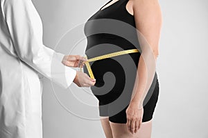 Doctor measuring fat woman`s waist