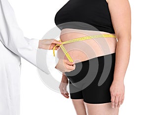 Doctor measuring fat woman`s waist on white background, closeup.