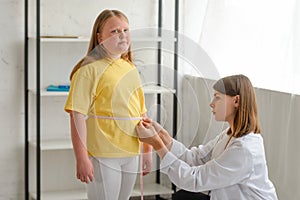 Doctor measuring girl& x27;s waist, checking the results of a diet