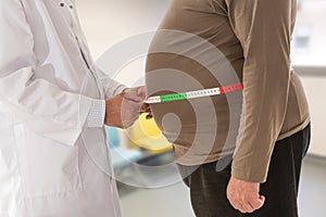 Doctor measuring obese man waist body fat. Obesity and weight loss.