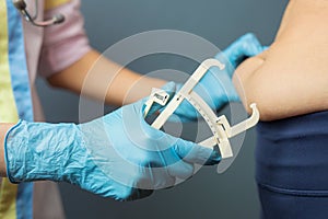 Doctor measuring patient`s tummy fat with a caliper
