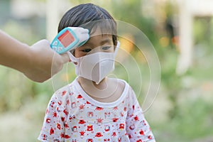 Doctor measuring temperature cute baby boy at hospital . Mother takes temperature for baby boy with Infrared Forehead Thermometer