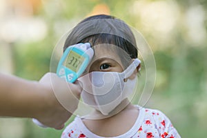 Doctor measuring temperature cute baby boy at hospital . Mother takes temperature for baby boy with Infrared Forehead Thermometer