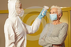 Doctor measuring temperature of an elderly lady using non-contact thermometer